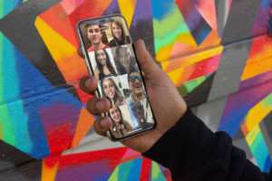 Smartphone mit Gruppen-Videocall mit bunter Wand im Hintergrund